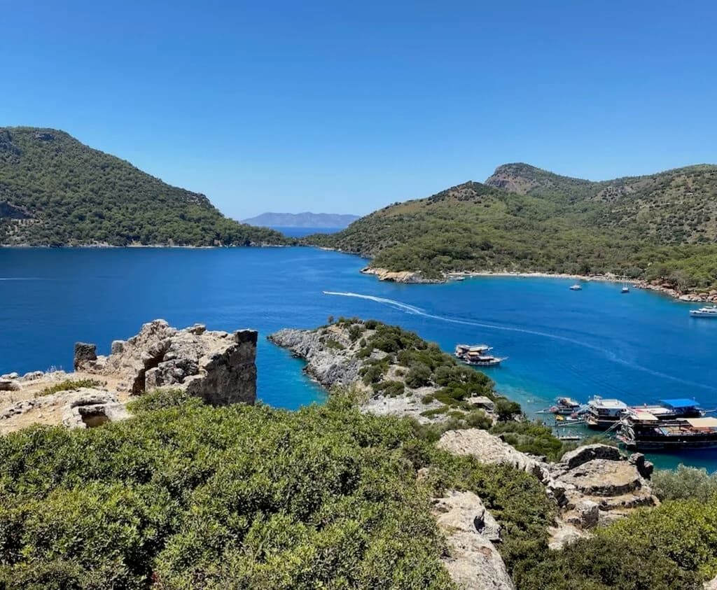 Boats moored in the channel off St Nicholas Island, with the hillside ruins above