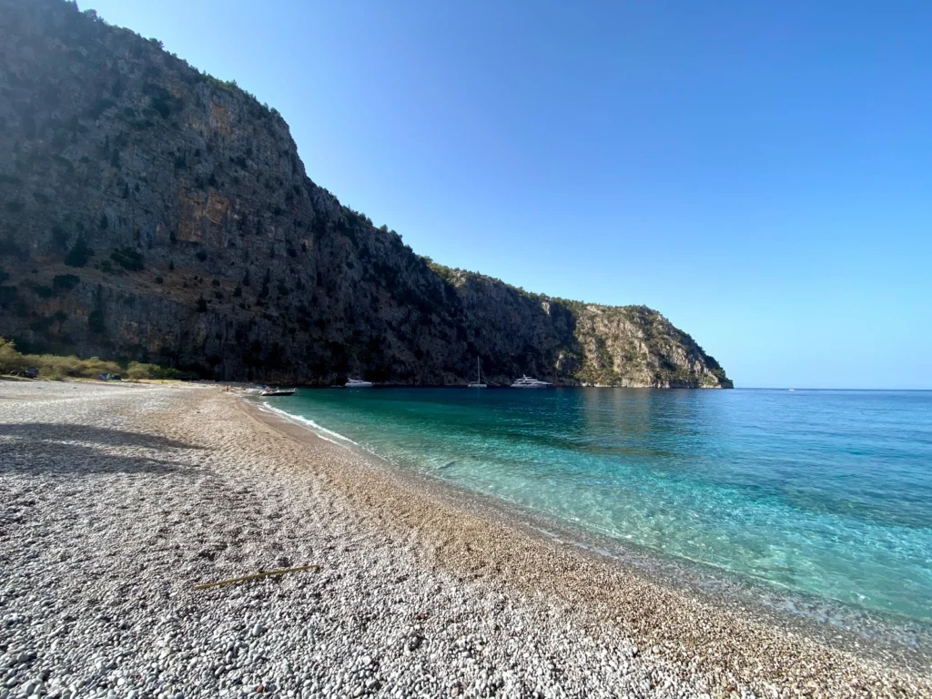 Pebble shoreline and clear water inside Butterfly Valley